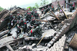 Rescue workers sit on the debris of destroyed houses after a strong earthquake at Longmen village in Lushan county of Sichuan province on Saturday. 