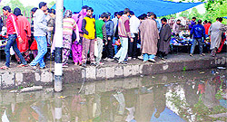 People walk on a footpath close to a puddle in Srinagar