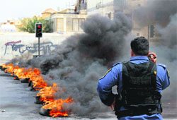 A riot police officer stands in front of a line of burning tyres after clashes with pro-democracy activists in Manama, Bahrain, on Sunday. 