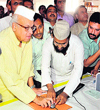 Governor Aziz Qureshi clicks the computer mouse to start the lottery to select Haj pilgrims in Dehradun on Monday