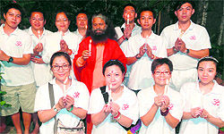 Swami Chidanand Muni along with foreign tourists lights candles adjacent to the Ganga at Parmarth Niketan in Rishikesh on Monday