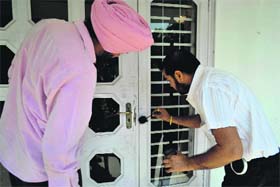 Forensic experts lift fingerprints from the door of the house where a theft took place in Ludhiana on Tuesday