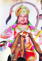 Fans offer sweets to a poster of Sachin Tendulkar, depicted as Lord Hanuman, ahead of his 40th birthday in Allahabad.