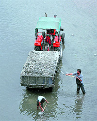 Labourers collect sand from the Tawi river in Jammu on Wednesday