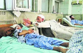 An Afghan man sits near his grandson, wounded due to a 5.6 magnitude earthquake, in a hospital in Jalalabad, Afghanistan, on Wednesday