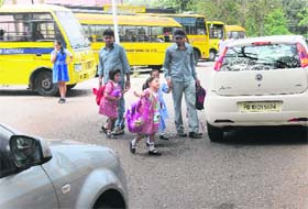 A girl signals a car to stop so that she can cross the road in front of Carmel Convent School, Sector 9, Chandigarh, on Thursday
