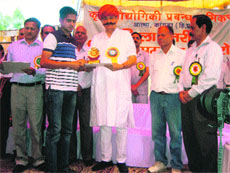 Agriculture Minister Sujan Singh Pathania honours a farmer at a camp in Rehan near Nurpur on Thursday. 