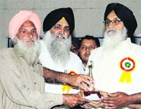 Punjab CM Parkash Singh Badal gives a memento to a member of a village committee in Chandigarh on Thursday. 