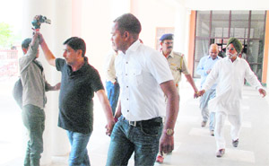 An accused (in black T-shirt) manhandles a cameraperson in the presence of policemen at the Panchkula Court on Friday. 