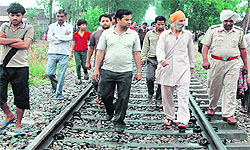Policemen and residents inspect the railway track where the two students jumped before a train
