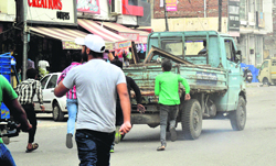 Shopkeepers chase an MC truck full of confiscated goods in the Jawahar Nagar Camp area of Ludhiana on Saturday.