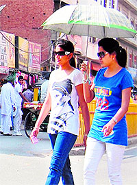 Girls use an umbrella on a hot summer afternoon in Amritsar on Sunday