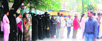 Women voters wait for their turn at a polling booth in Dehradun on Sunday.