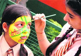 A girl paints 'Save girl child' message on a co-contestant's face during a face-painting contest in Jalandhar