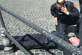 A police officer lies on the ground after gunshots were fired in front of Chigi Palace in Rome on Sunday