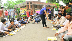 Students serve lunch to the needy outside the main gate of the National Institute of Pharmaceutical Education and Research in Mohali on Monday.