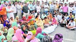 Relatives of deceased Deepak Kumar, along with villagers, block NH-1 near Samanabahu in Karnal district on Monday. Tribune photo: Ravi Kumar 