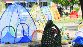 A woman vendor selling mosquito nets waits for customers on a hot afternoon in Karnal.
