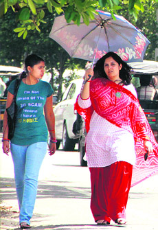 Women take shade under an umbrella as mercury soars in Jalandhar on Monday.