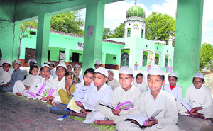 Students study in an NCLP school run in the verandah of a madarsa at Jamsher Khas village in Jalandhar. A mosque is seen in the background. 