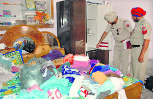 Police officials inspect the house in Randhawa Masanda village where the theft took place in Jalandhar on Monday.