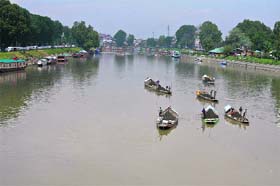 Sand digger collects sand from the riverbed in khoech (big boats) in Srinagar on Monday