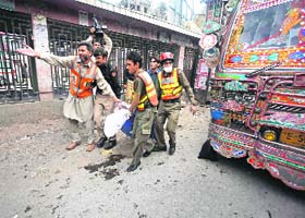 Rescue workers carry a victim of a bomb blast on the University Road in Peshawar on Monday