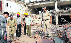 Policeman and other officials inspect the debris of a three-storeyed building which collapsed in Udyog Vihar, Phase-2, in Gurgaon on Tuesday. Three labourers were injured in the collapse
