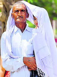 A man tries to protect his child from the scorching Sun on a hot afternoon in Karnal on Tuesday