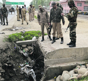 Army soldiers and policemen inspect the site where the IED was found under a culvert on the Srinagar-Baramulla highway on Tuesday. 