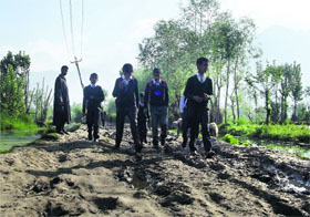 Schoolchildren walk on a muddy road at Mir Behri in the middle of the Dal Lake in Srinagar on Tuesday.