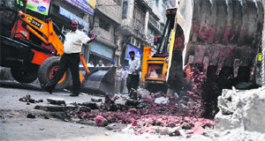 An earth-moving machine of the MC demolishes an illegal structure in the Saban Bazaar area on Tuesday