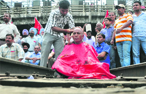 An activist of the Northern Railways Men's Union gets his head shaved during a protest at the Ludhiana railway station on Tuesday.