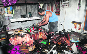 A worker looks at the charred remains after a fire broke out at a shop in Sector 23, Chandigarh, on Wednesday.