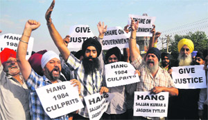 Protesters shout slogans and hold placards against Congress leader Sajjan Kumars acquittal in a case relating to the 1984 anti-Sikh riots, in Jammu on Wednesday. 