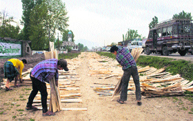 Workers collect strips of wood left for drying on a roadside on the outskirts of Srinagar. These are used for making plywood sheets.