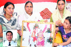 Family members of Rinku Suman (inset) with a photo of his wedding at their house in Jalandhars Sikanderpur village