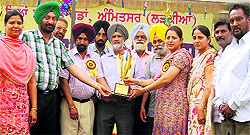 Olympian Brig Harcharan Singh and AEO S Kuljinder Singh Malhi present the winners trophy to principal Mandeep Kaur in Amritsar on Thursday