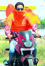 A youth covers his face while riding a bike on a hot afternoon in Amritsar on Friday
