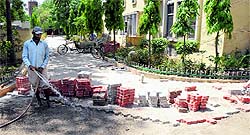 A worker waters the tiles being used to lay a path at Government Rajindra College in Bathinda on Friday