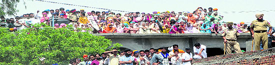 Residents climb atop rooftops to have a glimpse of his body