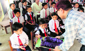 Manager, SBI, Udesh Bhandari distributes chocolates among students of Nanhi Dunya School in Dehradun on Saturday.