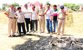 Police personnel look at the mortal remains of a woman at Ramnagaria village in Sirsa district on Saturday.