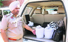 A policeman shows the heroin seized from Gurdev Singhs (right) car in Jalandhar on Saturday.
