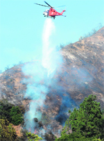 water drop: A fire-fighting helicopter makes a water drop in California. Hundreds of firefighters continue to battle the wildfire that has affected 18,000 acres. AFP