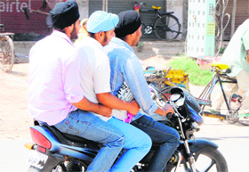 Youths violate traffic norms by triple-riding on a motorbike in Amritsar on Sunday.