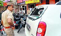 A cop looks at the damaged windshield of a car in Bathinda on Sunday