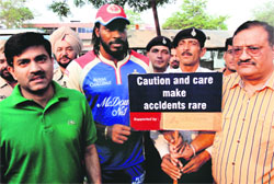 International cricket player Chris Gayle holds a placard with traffic policemen at Sector 35, Chandigarh, on Sunday. 