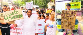 Mayor Vinod Chamoli at a rally organised by Waste Warriors against pasting of election posters on walls in Dehradun on Sunday; and (right) a boy shows a placard with a message