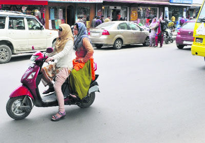  Women ride through a market on a scooty in Srinagar on Sunday. 